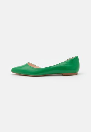 Zapato plano de cuero verde con punta puntiaguda y suela baja marrón, fotografiado de perfil sobre un fondo blanco.