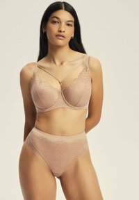 Jasnobeżowy zestaw bielizny z kwiatowymi koronkami, z solidnym biustonoszem z regulowanymi ramiączkami i dopasowanymi wysokimi majtkami.