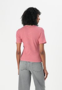 Cămașă cu dungi roșii și albe, cu mânecă scurtă, design ajustat, din material de bumbac, cu guler rotund, asortată cu pantaloni din denim gri deschis.