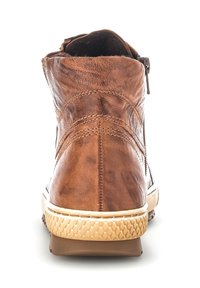 Botte chelsea en cuir marron avec une surface texturée, des coutures contrastées et une semelle en caoutchouc avec un motif de semelle. Détail de fermeture éclair sur le côté.