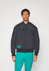 Μαύρο μπουφάν μπομπέρ με φερμουάρ εμπρός, μανσέτες με ριπ ύφανση και τιρκουάζ λεπτομέρειες, συμπεριλαμβανομένου λογότυπου και ετικέτας. Υλικό με υφή και ελαφρύ σχεδιασμό.