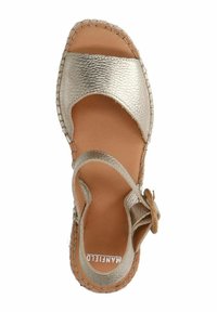 Metallische gouden sandaal met kruislingse banden, een geweven rand en een platte zool, met een bloemenaccent en een textuurleer ontwerp.