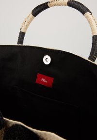 Borsa tote intrecciata con un design nero e beige. Presenta un manico intrecciato resistente, un interno nero, una chiusura a scatto e un'etichetta rossa.