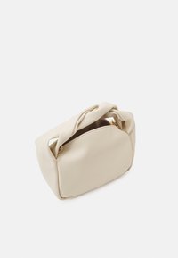 Bolsa de mano beige hecha de material sintético suave, con un asa anudada, forma redondeada y detalle de cremallera en tono dorado en la parte superior.