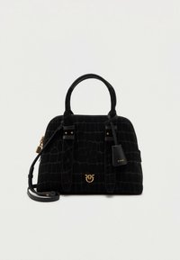 Musta nahkalaukku krokotiilikuviolla, kaksin käsikahvoin, kultaisella logolla ja irrotettavalla olkahihnalla vaalealla yksivärisellä taustalla.