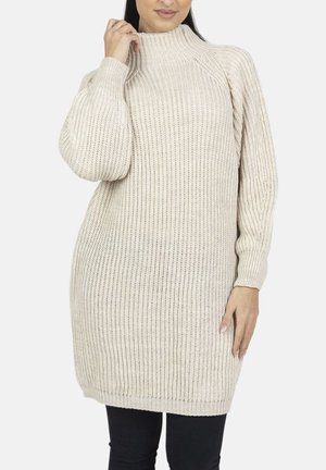 Strikket sweater i lys beige med høj hals, ribbet tekstur, afslappet pasform og lange ærmer, kombineret med sorte bukser.