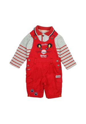 Salopette rouge avec broderie de visage de chat et boutons, associée à une chemise à manches longues rayée grise avec col et accents marine.