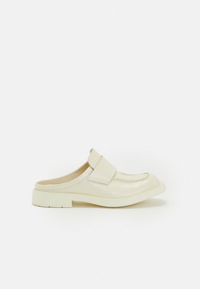 Krämfärgade slip-on skor med rund tå, mjuk läderfinish och ett brett band över ovansidan. Kraftig gummisula.