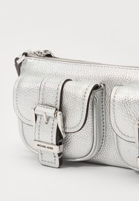 Borsa a tracolla in pelle argentata testurizzata con due tasche frontali, un accento a fibbia e una chiusura con zip. Presenta il dettaglio del logo del marchio.