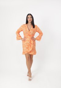 Orangenes Blumen-Wickelkleid mit langen Ärmeln, ruffled Saum und tiefem V-Ausschnitt. Leichter Stoff, der mit kleinen weißen Blumen durchzogen ist.