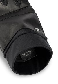 Zwarte leren handschoen met een zachte stofvoering, een gladde textuur en een metalen accent met het merklabel "ROECKL MÜNCHEN."