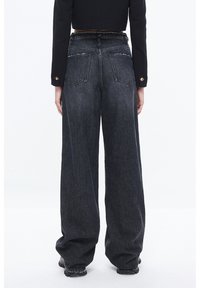 Pantalones de mezclilla de pierna ancha, en gris oscuro, con cintura alta, dobladillo sin rematar y costuras en contraste; cuenta con dos bolsillos traseros y un acento de cadena.
