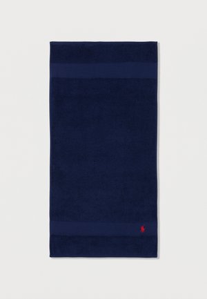 Toalla rectangular azul oscuro con dos bandas horizontales texturizadas, con un pequeño logo bordado de un jugador de polo rojo cerca de la esquina inferior derecha.