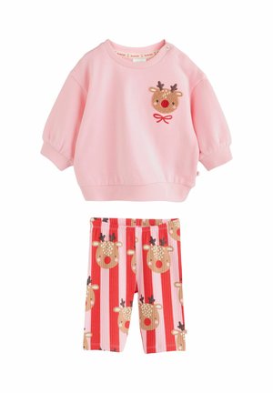 Maglietta rosa a maniche lunghe con un viso di renna e dettaglio con fiocco rosso, abbinata a pantaloni a righe rosse e rosa con un motivo di facce di renna ripetute.