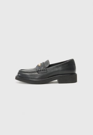 Mocassins de couro preto com um detalhe trançado no peito do pé, um logótipo dourado e uma sola espessa em borracha preta. Textura suave com ligeiro brilho.
