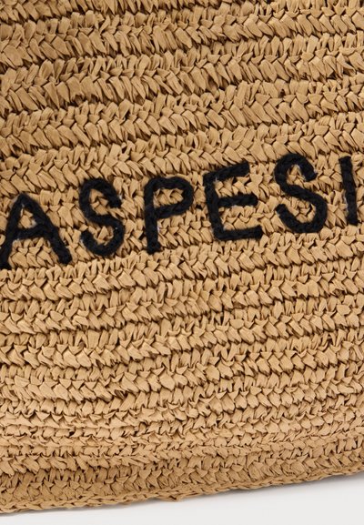 Κοντινό πλάνο μπεζ υφαντής τσάντας από άχυρο με μαύρη κεντητική κλωστή που σχηματίζει τη λέξη "ASPE" σε υφή επιφάνειας.