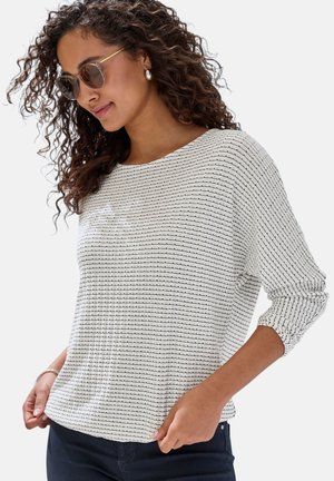 Lightweight, long-sleeve top in white with black horizontal stripes, round neckline, and relaxed fit. Model wearing sunglasses and earrings.