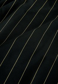 Tissu noir avec fines rayures verticales dorées, présentant une texture lisse et un léger éclat. Les rayures sont uniformément espacées et fines.
