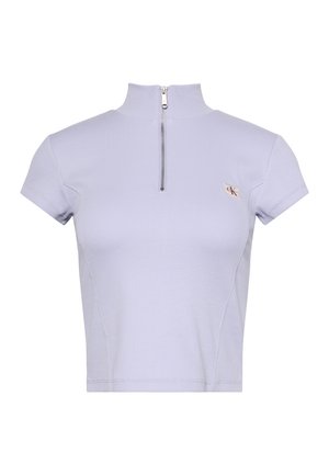 Camiseta corta de manga corta de color púrpura claro con cuello alto, cremallera plateada frontal y pequeño parche con logo en el pecho izquierdo.