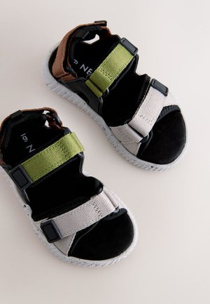 Sandalias negras y grises con correas ajustables en verde y marrón, con suela texturizada y plantilla acolchada para mayor comodidad.