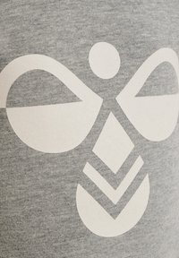 Grått tyg med en strukturerad yta som har en stor vit grafisk design av cirklar och chevroner. Mönstret är centrerat och iögonfallande.
