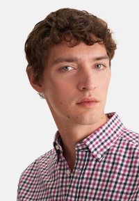 Camicia button-down con un motivo a quadri nei colori rosa, blu navy e bianco. Presenta un colletto e piccoli bottoni. Il tessuto sembra morbido e leggero.