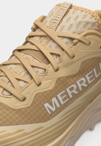 Αθλητικό παπούτσι Tan Merrell με μπεζ κορδόνια, διχτυωτό επάνω μέρος και έντονη λευκή σήμανση στο πλάι και στη γλώσσα.