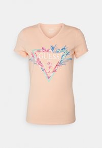 Abrikosfarvet V-hals t-shirt lavet af bomuld, prydet med et blomstret trekantsgrafik i nuancer af pink og teal, med mærket "GUESS" logo.