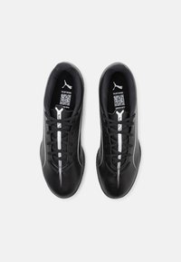 Scarpe sportive nere con una parte superiore in sintetico testurizzato, dettagli in bianco e un design a profilo basso con chiusura con lacci e logo.