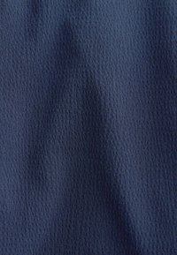 Tissu bleu marine avec une texture gaufrée subtile, montrant de légers plis et des ombres.