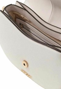 Interno di borsa in pelle bianca con più scomparti, dettagli in metallo dorato e tasca con cerniera per l'organizzazione. Dettagli testurizzati visibili.