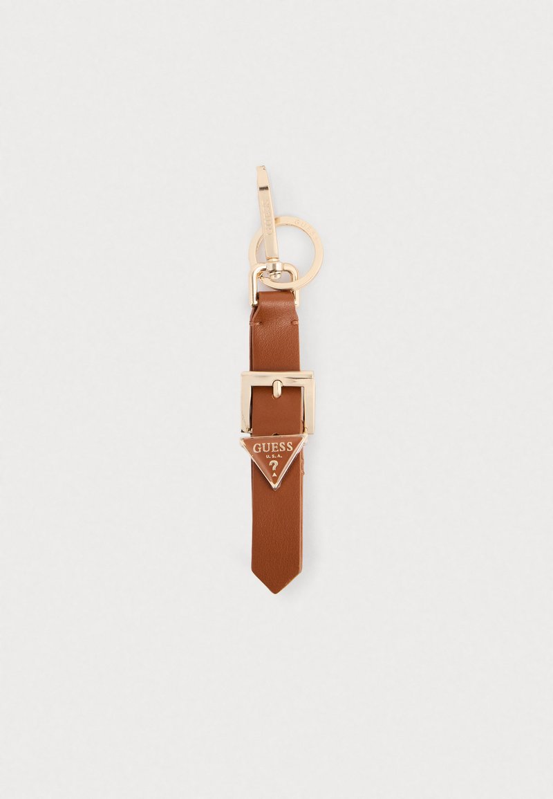 Porte-clé en cuir marron avec des finitions dorées, présentant une étiquette triangulaire embossée "GUESS U.S.A." ; texture lisse et extrémité pointue.