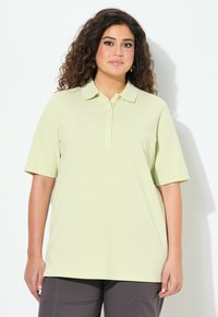 Světle žluté polo tričko s krátkými rukávy, límečkem a knoflíkovou légou. Hladká textura, uvolněný střih, vhodné pro volnočasové nošení.