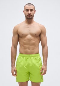 Pantalones cortos de baño verde lima con cintura elástica y superficie texturizada, que cuentan con paneles laterales de malla para mayor transpirabilidad.