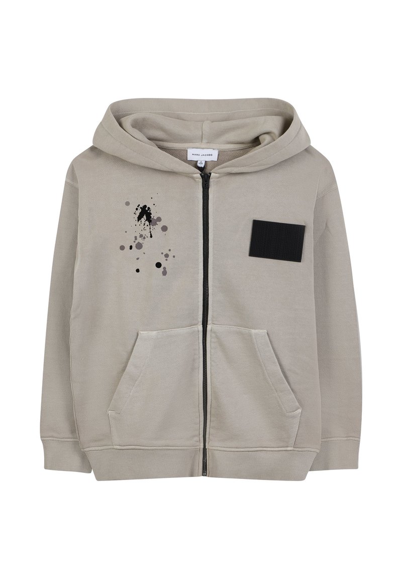 Helle beige Zip-Up-Hoodie aus Baumwollmischung, mit einer Fronttasche, schwarzem Stoffaufnäher und einem abstrakten Design aus schwarzem und grauem Farbspritzern.