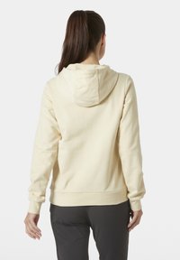 Sudadera ligera amarilla hecha de suave material de algodón, con capucha, puños acanalados y un corte relajado. La parte trasera es lisa, sin adornos.