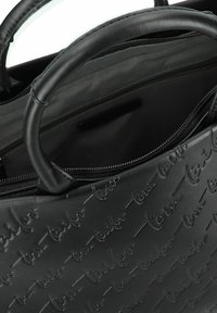 Bolso de mano de cuero negro con patrón de logo en relieve, asas dobles, cierre de cremallera y forro de tela en el interior. Textura suave y forma estructurada.