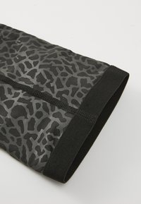 Leggings sportivi neri con un motivo a stampa animale grigia, realizzati in tessuto elasticizzato con una vita testurizzata.