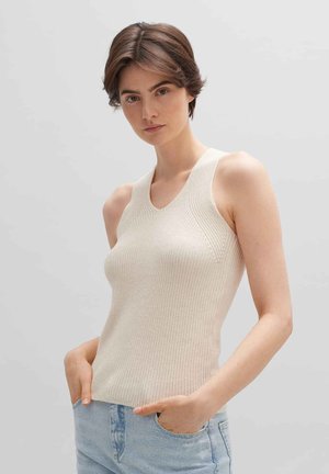 Beige geribbelde tanktop met brede banden, V-hals en textiel stof, gecombineerd met lichtblauwe jeans. Subtiele ontwerpelementen verbeteren de vorm.