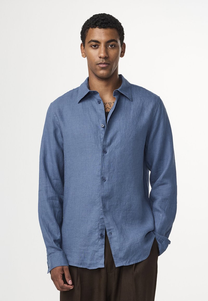 Light blue long-sleeve shirt made of textured linen, featuring a button-up front, pointed collar, and slightly loose fit.