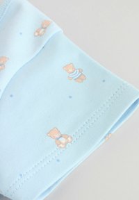 Tissu bleu clair avec de petits ours en peluche portant des nœuds et des chemises rayées imprimées, avec une double couture soignée le long du bord.