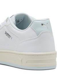 Baltas ādas sporta apavi ar gaiši zilu papēža detaļu. Satur sudraba logotipu sānos, teksturētu baltu zoli un mīkstu mēli komfortam.