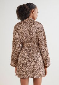 Leopardmönstrad morgonrock i mjukt material, med långa ärmar och knytskärp i midjan. Designen inkluderar ett bälte i midjan och en flödande silhuett.