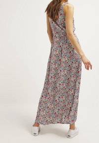 Květinové maxi šaty bez rukávů, s bílým pozadím a vícebarevnými květy. Měkká látka, volný střih a délka ke kotníkům.