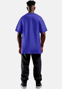 Korte mouwen, oversized paars T-shirt gemaakt van katoen, gecombineerd met zwarte broek; heeft een ronde hals en een relaxed fit.