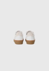 Sneaker bianche in pelle con suola in gomma brunita e texturizzata. Accenti in suede sul tallone, con un design minimalista e dettagli del logo.