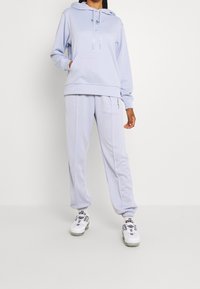 Ljusblå hoodie med en ficka fram och dragsko. Bekväma matchande sweatpants med elastiska ärmslut. Båda plaggen har logotypdetaljer.