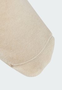 Pletená bé�žová ponožka s žebrovanou strukturou, měkkou tkaninou, zaoblenou špičkou a bezešvým designem, zdůrazňující pohodlí a jemnou barvu.