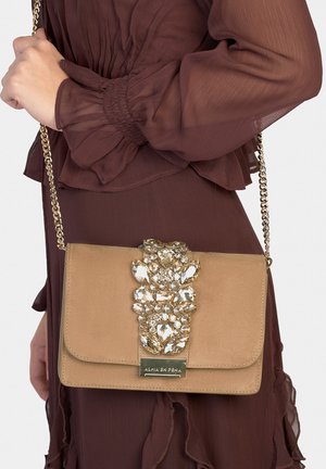 Beige Clutch mit goldener Kettenriemen und Schmuckverzierung auf der Klappe; gefertigt aus glattem Material mit poliertem Finish.