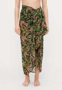 Blomstrete omslagsskjørt i gjennomsiktig svart stoff, med grønne blader og rosa blomster. Knyttet i livet, med et langt, svakt design.